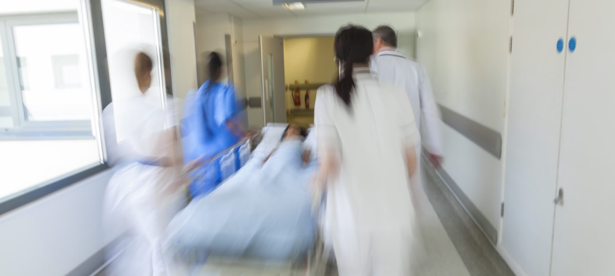 Health care staff pushing a patient on a gurney