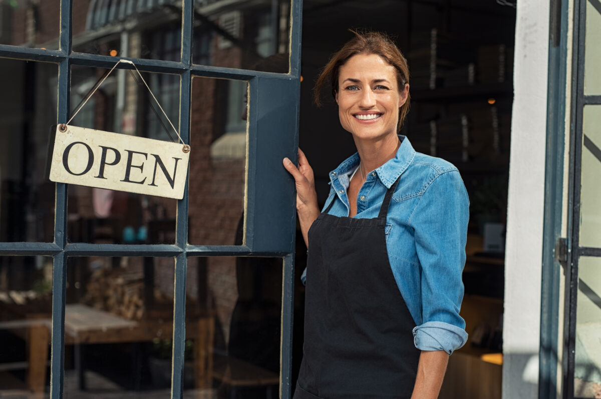 woman at shop door, open sign