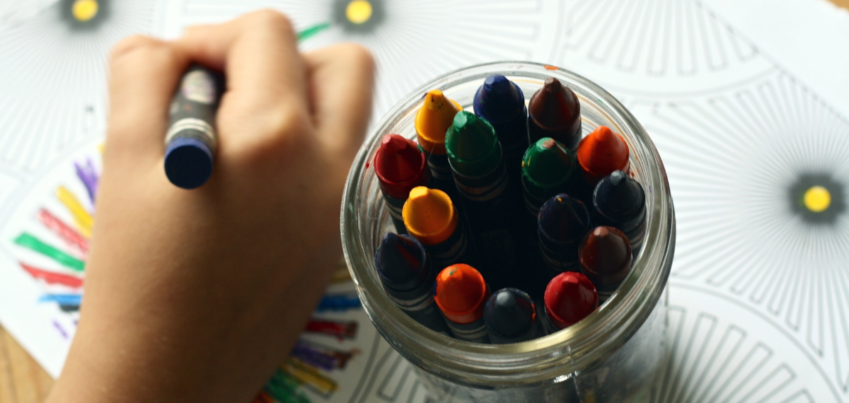 childs hand with jar of crayons