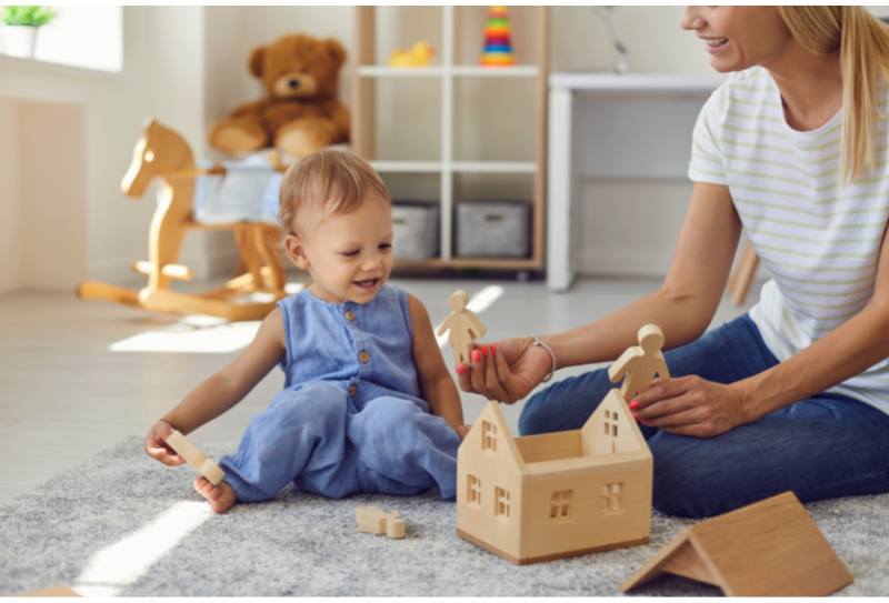 child and nanny playing with wooden toys